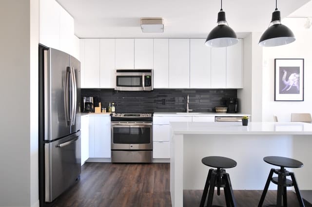 The use of dark dome-like pendant lights on a black and white kitchen.