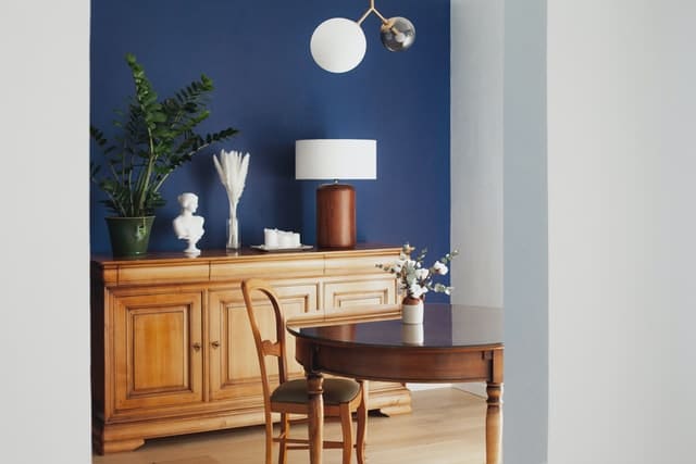 One accent wall painted with a rich blue color and some wooden furnitures.
