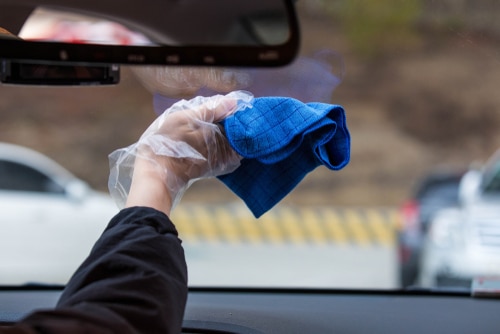 A hand wiping the front window using a blue microfiber cloth