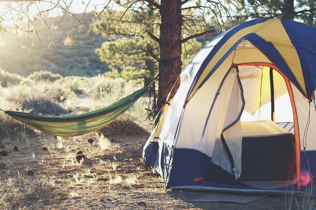 A camping tent beside a hammock during sunrise.