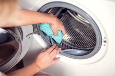 A person cleaning a dirty washing machine.