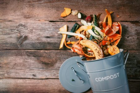 A compost can with materials that you can use spilling out of it