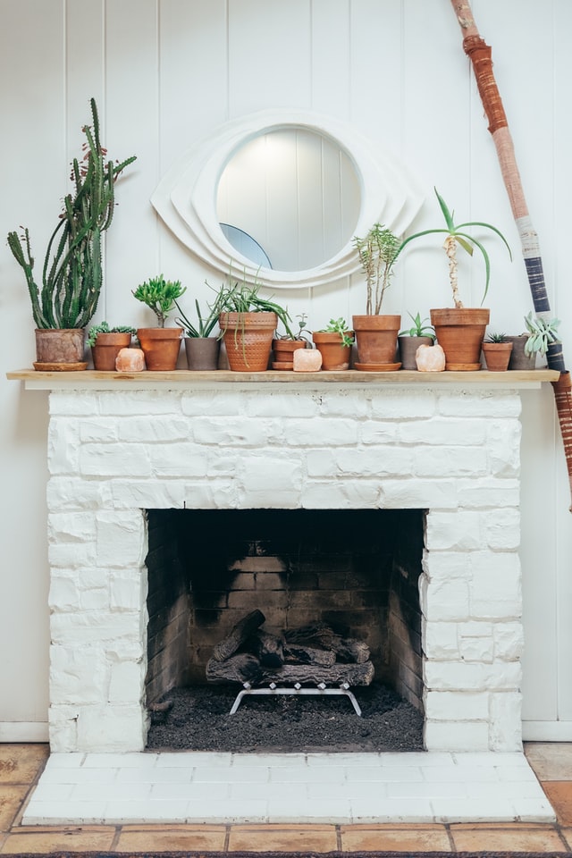A simple white indoor fireplace with a cottage aesthetic.