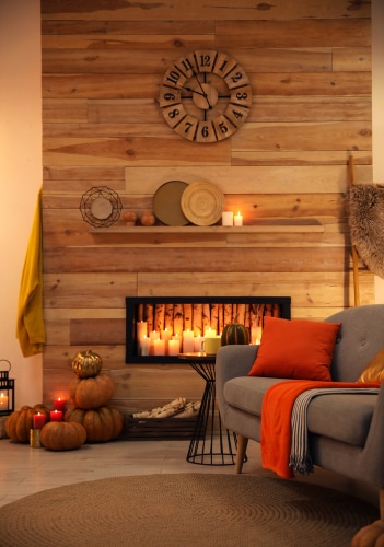 A cozy fireplace with pumpkins on the side
