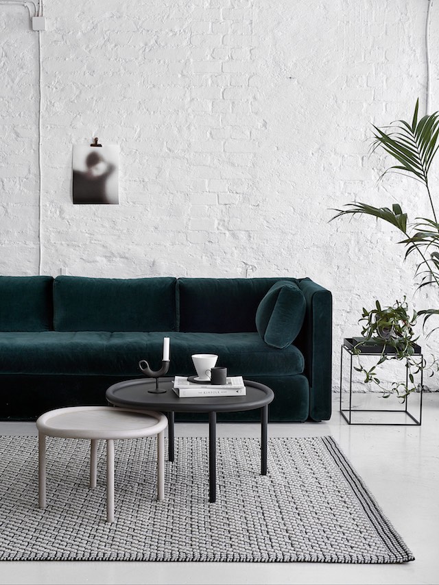 Dark green couch against a white painted brick wall