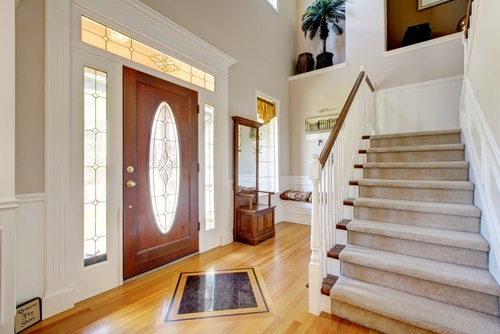 A nice entryway with a plain beige stairs carpet.