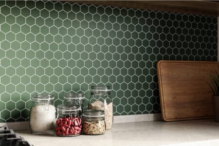 A green mosaic backsplash with spices on the counter