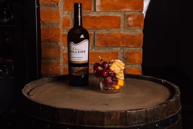 hillside wine a Hillside wine sitting on a wine barrell with a glass of grapes and cheese