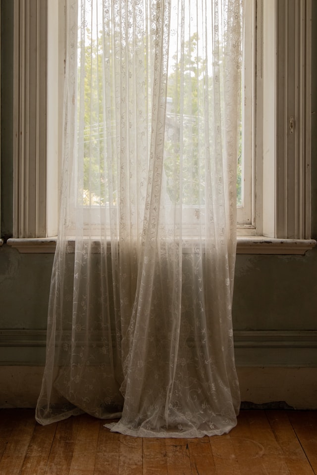 A floor length beige lace curtain.