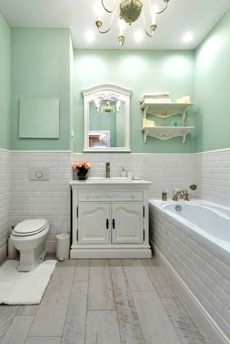 A light green and white comfort room with bath tub.
