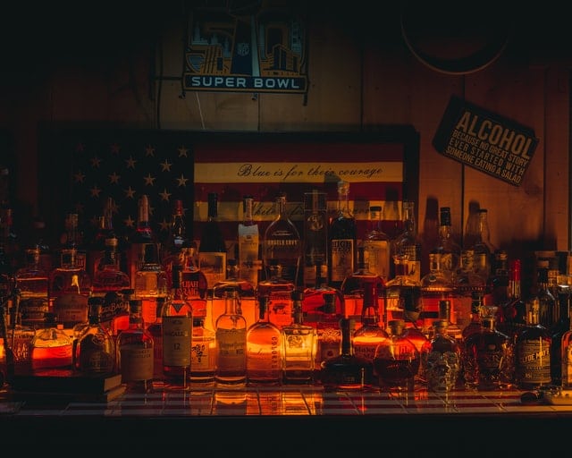 Plenty of liquor bottles and lighted candles on a bar counter