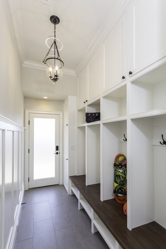 A long house entryway with plain white storage cabinets built along the way.