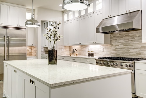 A luxurious white and marble kitchen interior with stainless appliances.