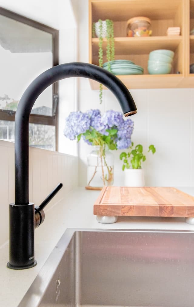 A matte black kitchen faucet against a stainless sink