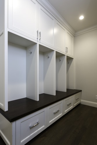A built in white cabinet in the mudroom with open shelving best as clothing or coat rack.