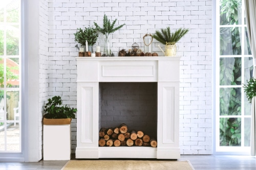 An old and white fireplace with woods that are yet to be burned.