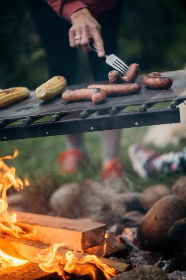 a man cooking corn and sausages
