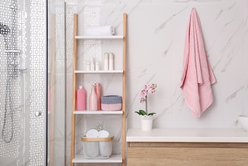 A white bathroom with pink towel and toilet accessories.