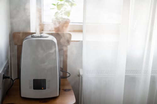 A room humidifier placed on top of a chair beside a window.