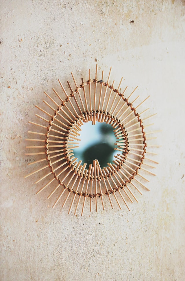 A round mirror framed by wooden sticks against the wall
