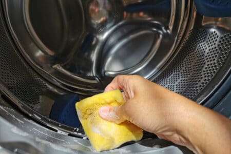 Closeup pic of a hand scrubbing a washer with sponge