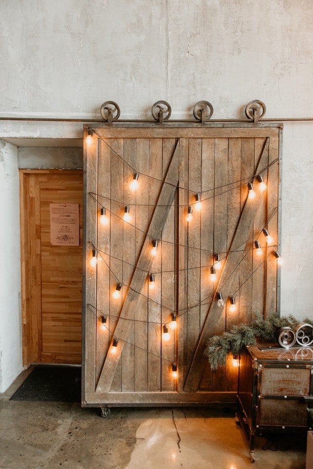 A wooden sliding barn door with hanging edison lightbulbs.