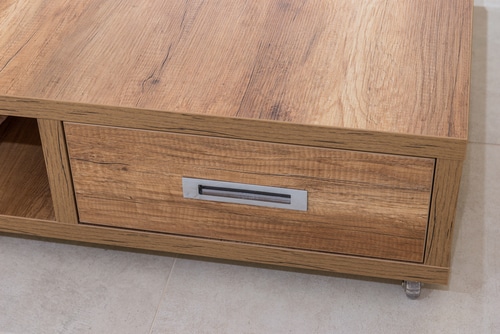 A wooden coffee table with a hidden functional drawers on the side.