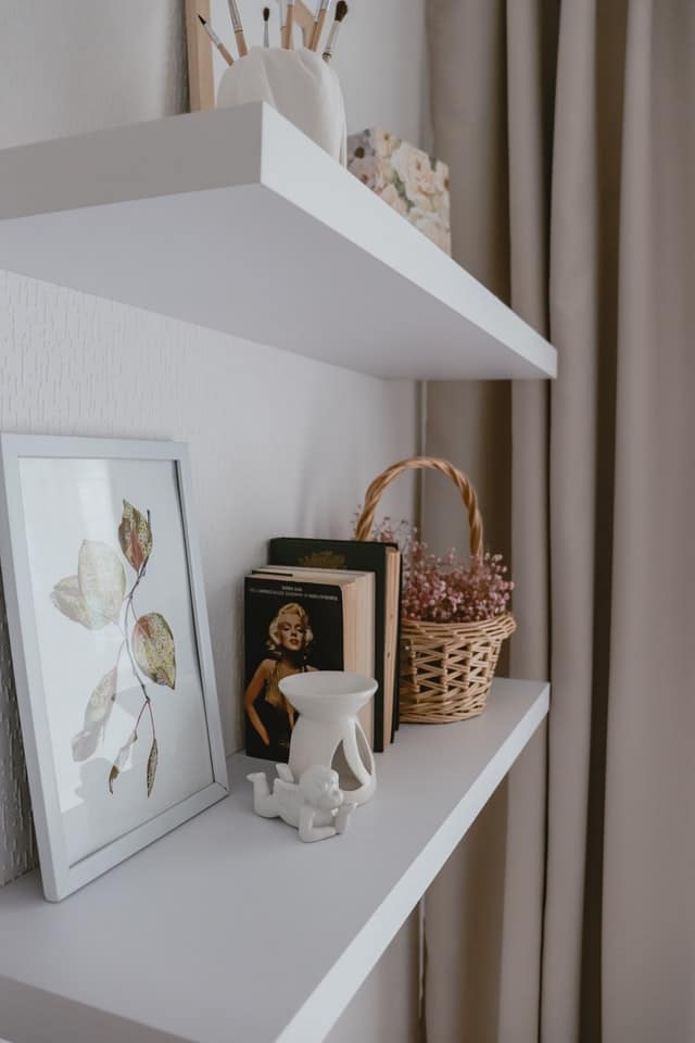 White floating shelves containing woven baskets and other decors