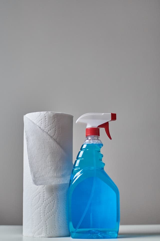 A bottle of cleaning spray beside a paper towel