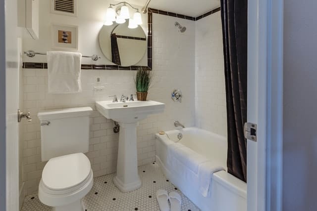 A white toilet and bathroom with mirror and towel rack.
