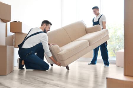 Two delivery men lifting a beige couch