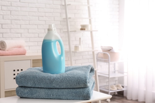 A liquid detergent bottle on top of a freshly washed towel.