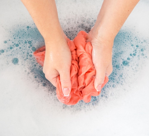 A woman's hand washing an orange cloth