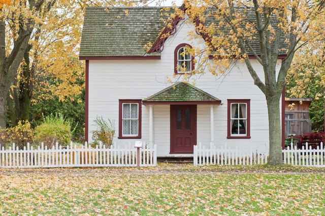 A white picket fence around a small family house.