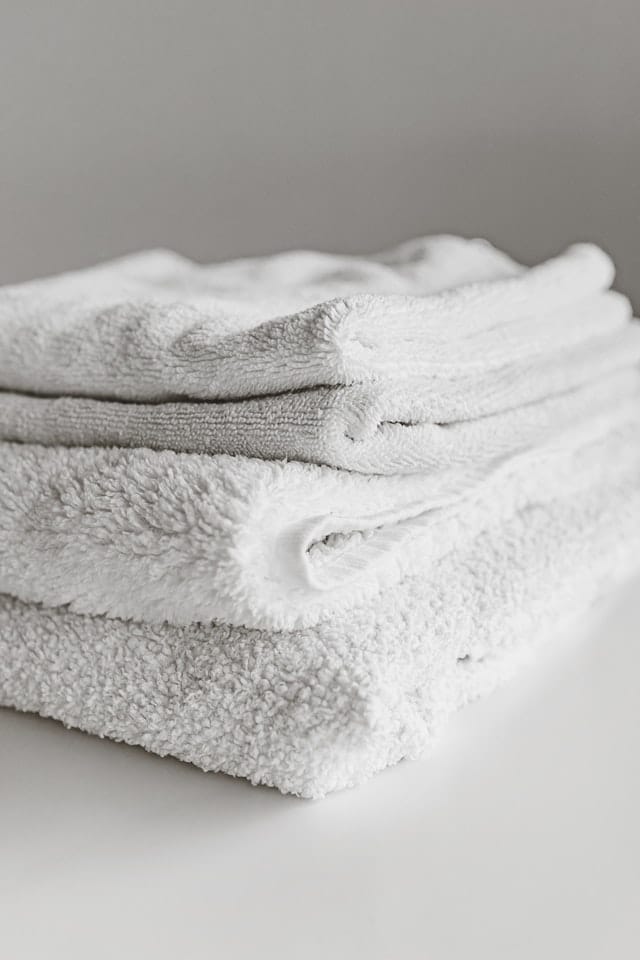 A stack of white towels on a white table.