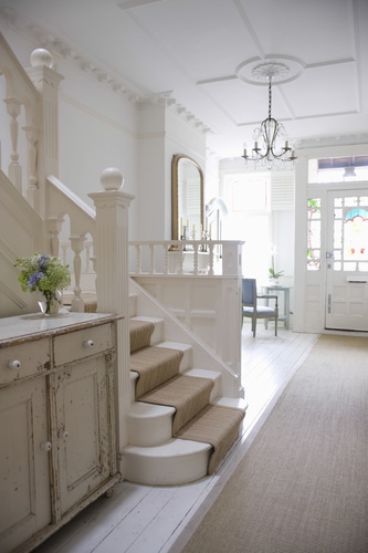 A white entry hall winder stairs with a soft beige fiber carpet.