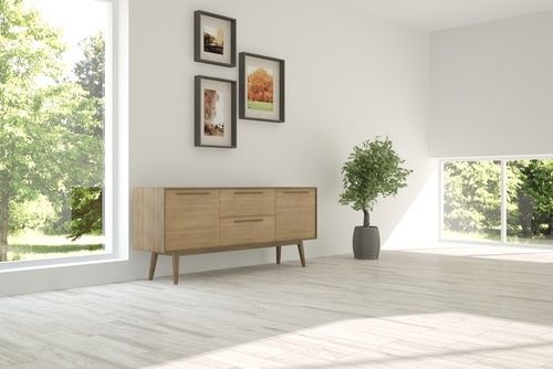 A wooden cabinet against a plain white wall with frame decors.