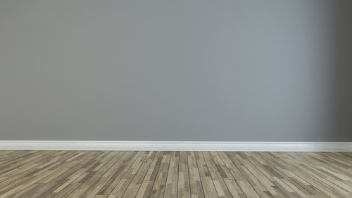 A plain gray wall against a natural wood flooring.