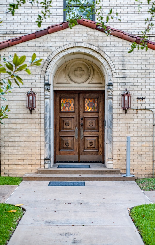 A wooden church door with a stained glass details.