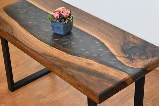 A wooden table with one fake plant sitting on top