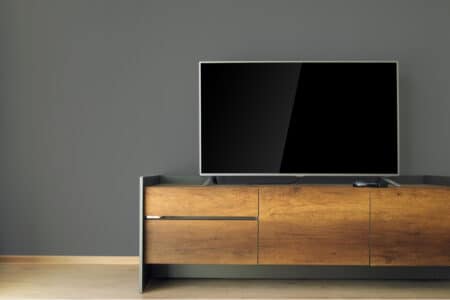 A wooden tv console against a gray wall